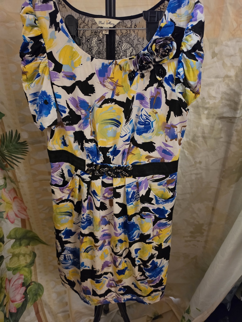 Pink Mary dress with abstract floral print in yellow, blue, and purple on a crea